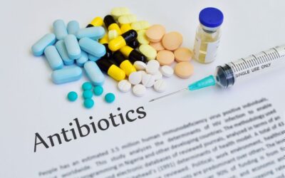 pagina di articolo con titolo "antibiotics" con sopra delle pillone sparse, una fiala piena e una siringa